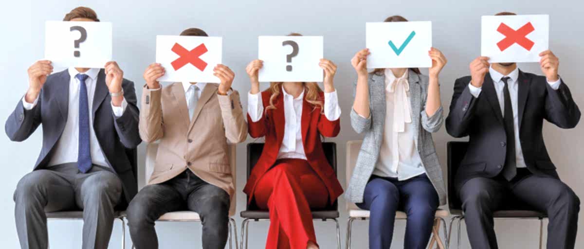 iş görüşmesi bekleyen adaylar; ellerinde üzerlerinde "?", "X" ve olumlu anlamda "check" işareti olan kartlar