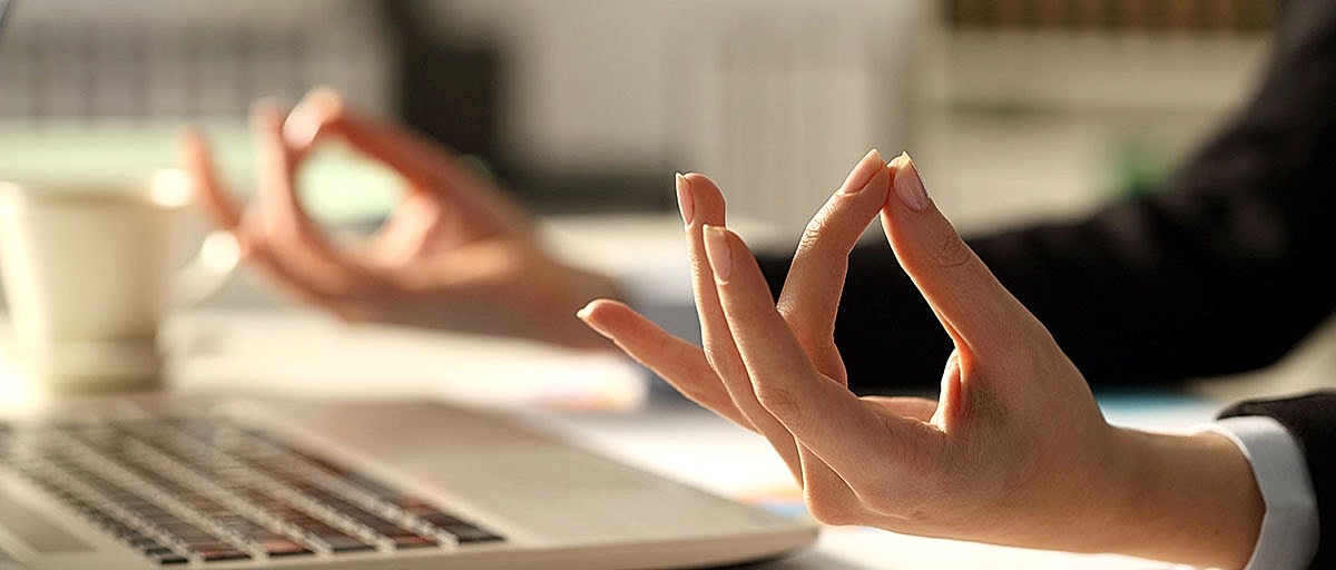 Ofiste, masa başında meditasyon yapan bir çalışanın ellerine yakın çekim.